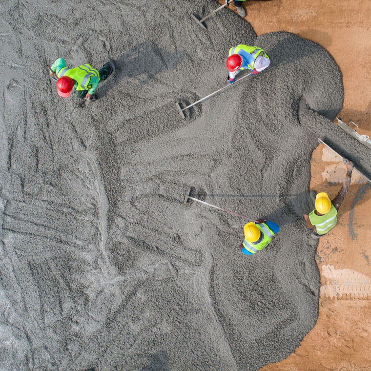 Bauarbeiter beim Gießen von nassem Beton auf einer Straßenbaustelle