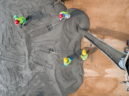 Bauarbeiter beim Gießen von nassem Beton auf einer Straßenbaustelle