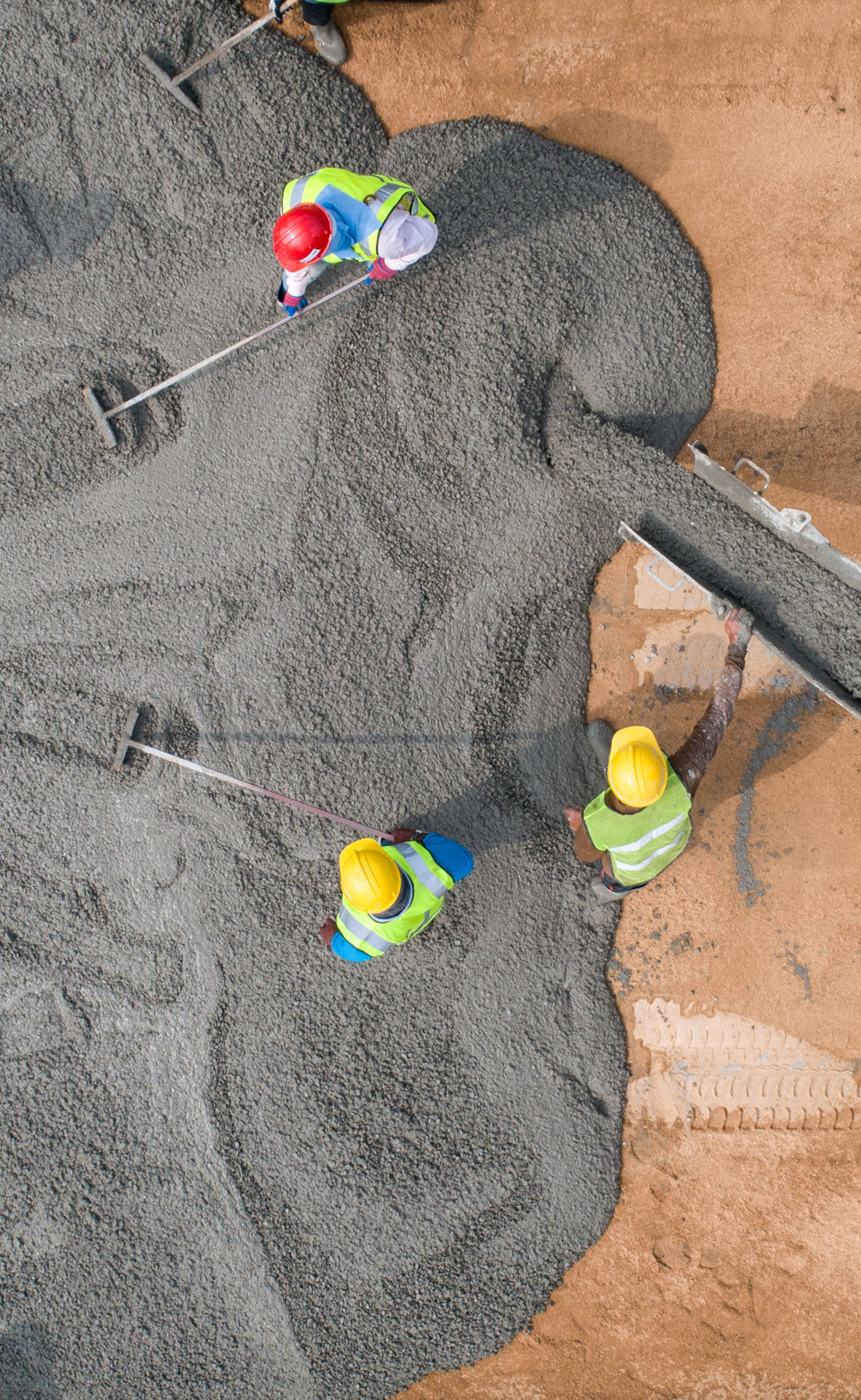 Bauarbeiter beim Gießen von nassem Beton auf einer Straßenbaustelle
