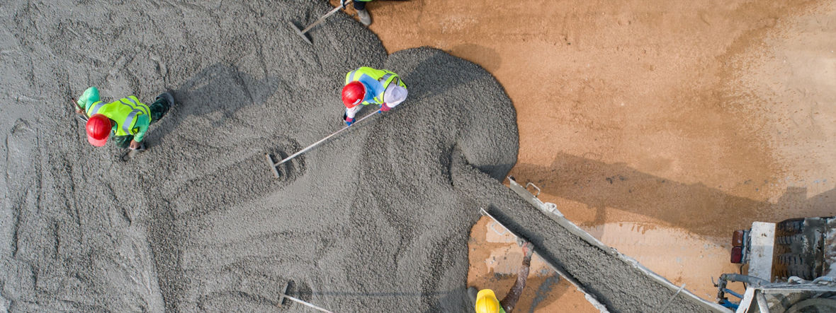 Bauarbeiter beim Gießen von nassem Beton auf einer Straßenbaustelle