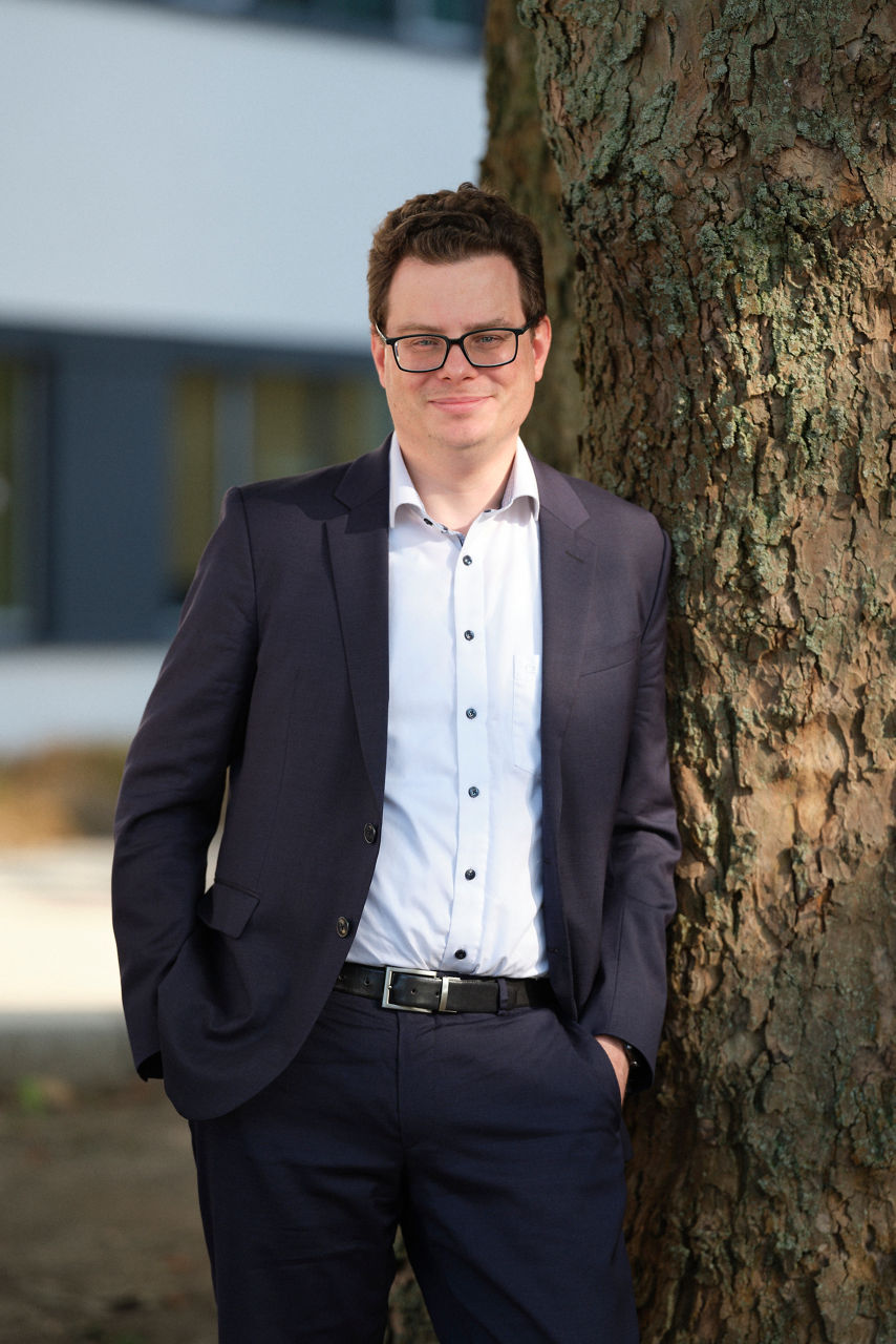 Christian Schirrmacher is leaning against a tree in a dark suit.