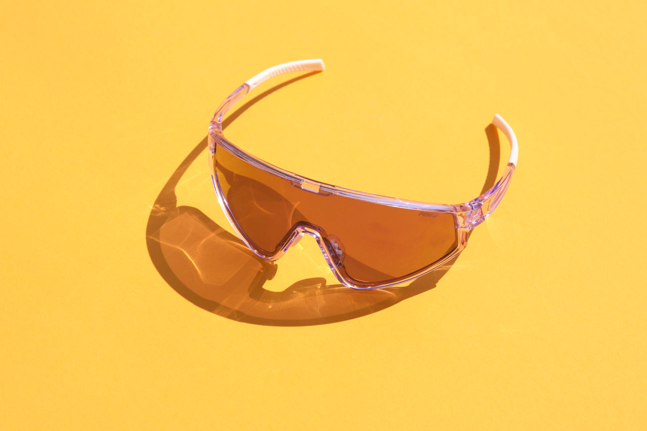 A transparent, light brown pair of sunglasses on a yellow background.