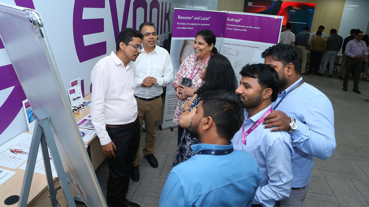 A group of professionals discussing products at an Evonik display during an event.