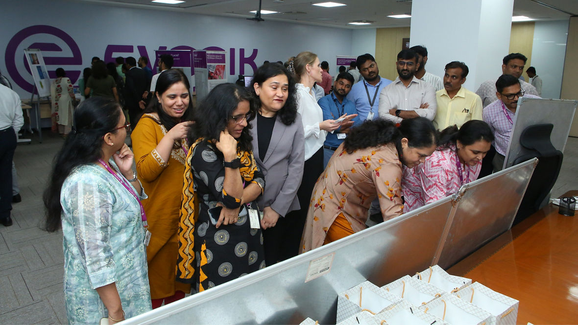A group of employees engaged in conversation and activities at an event in an office setting.