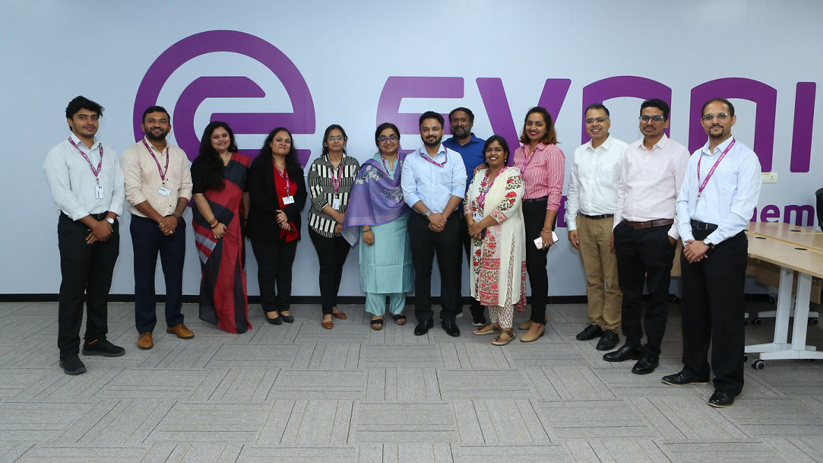 Group photo of employees posing in front of the Evonik logo, showcasing teamwork and collaboration.