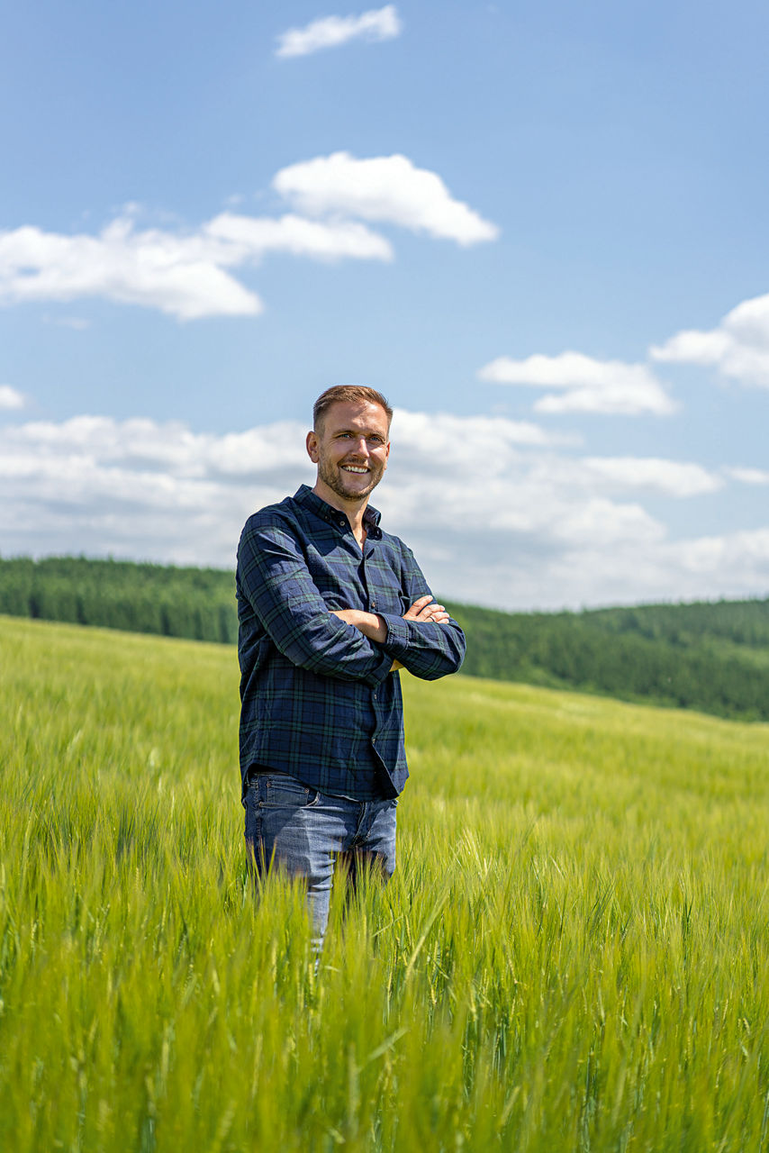 Andreas Dörr steht mit verschränkten Armen auf eiem grünen Feld.
