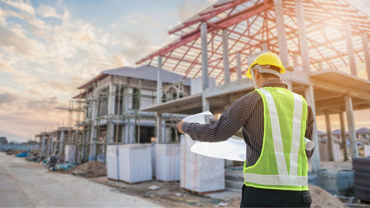 Professional engineer architect worker with protective helmet and blueprints paper at house building construction site background