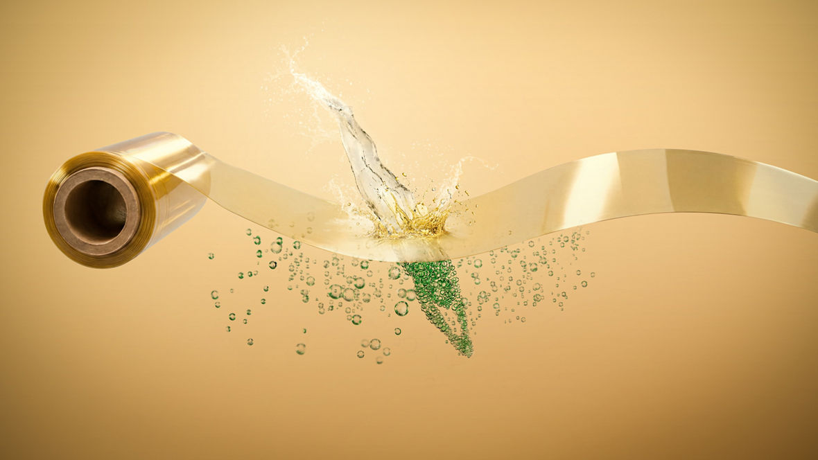 A transparent roll of film with a splash of liquid and green bubbles beneath it.