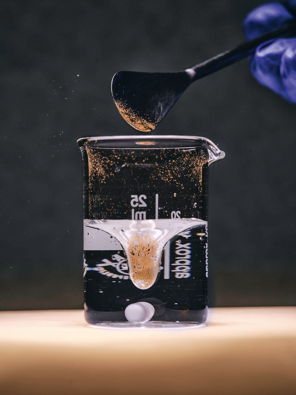 In ein laufendes Rührglas wird Pulver gegeben.