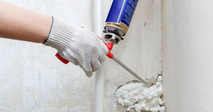 Applying one-component PU foam to fill wall gaps for insulation and sealing