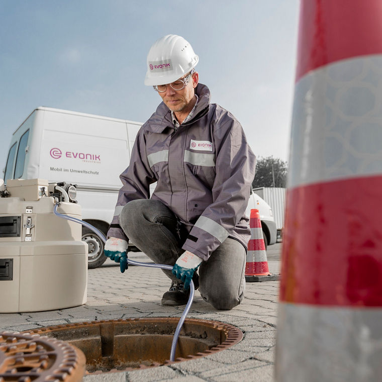 Ein Evonik-Mitarbeiter entnimmt eine Probe Wasser aus einem Abwasserschacht.