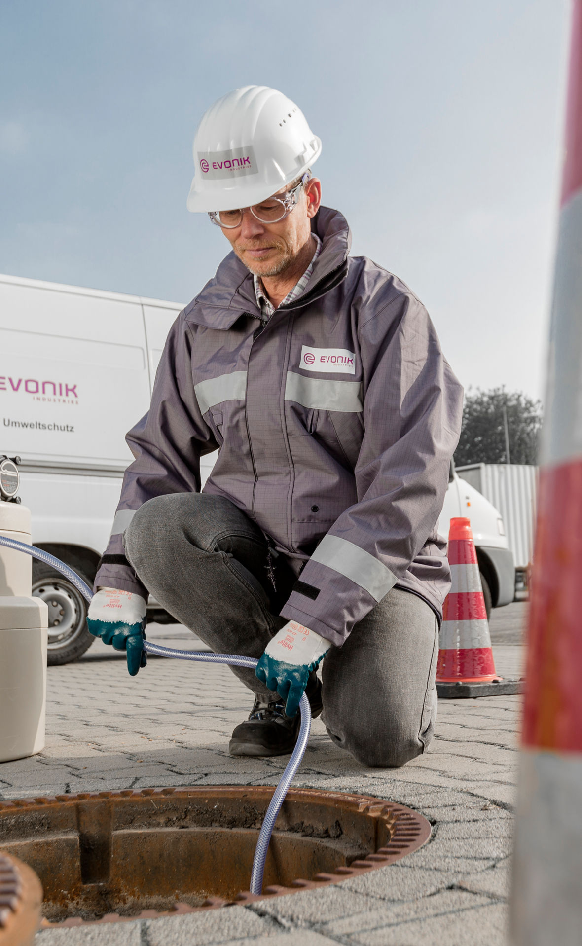 Ein Evonik-Mitarbeiter entnimmt eine Probe Wasser aus einem Abwasserschacht.