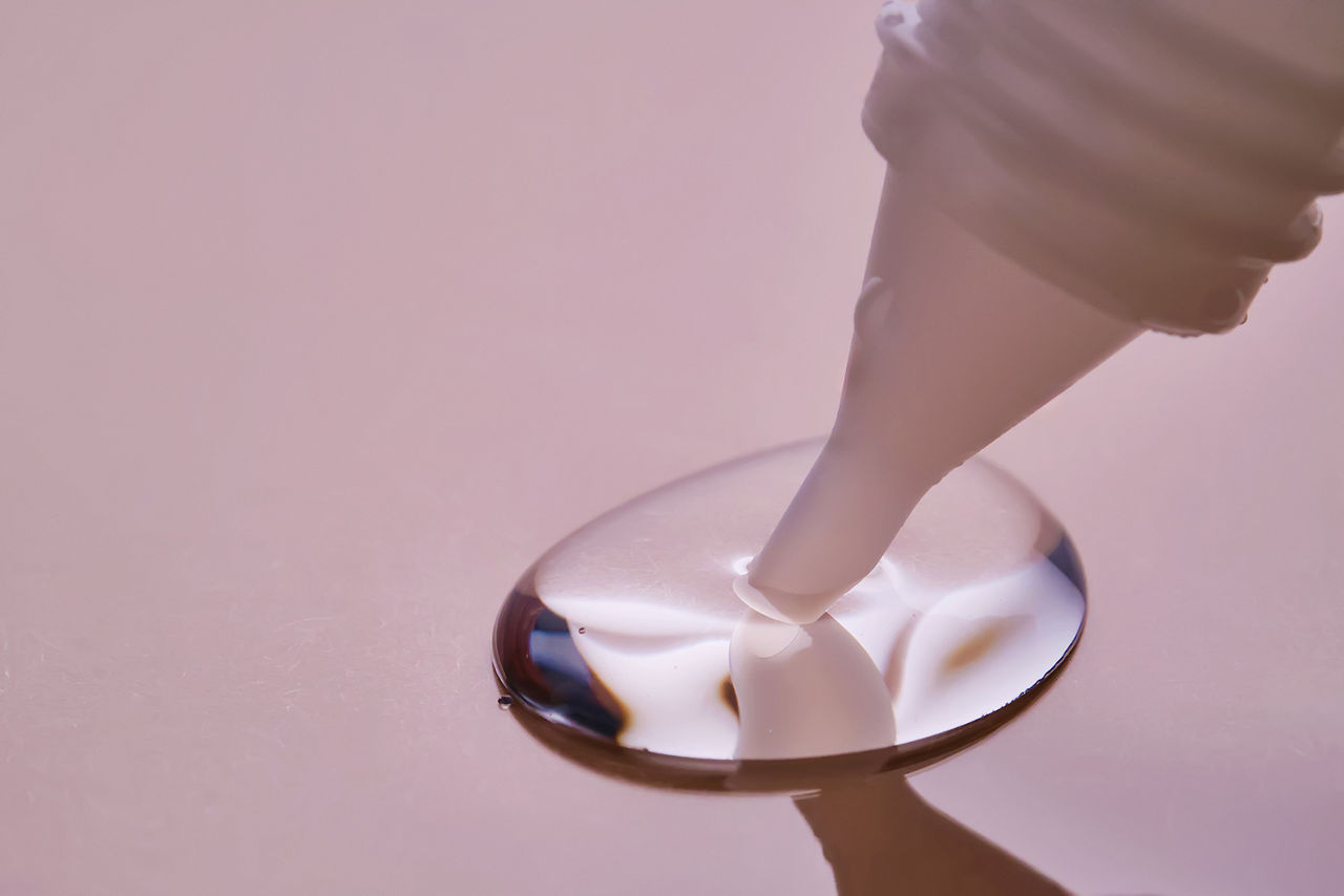 Stationery glue flows onto pink paper. High quality photo