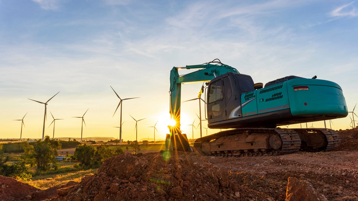 Excavator at a construction site with wind turbines 