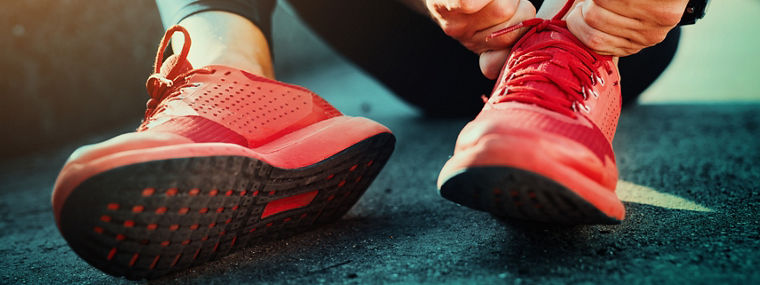 Person tying red athletic shoes—representing Evonik’s PU additives for durable, stylish, and high-performance microcellular foam products.