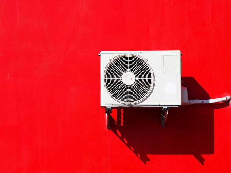 An air conditioner on a red wall