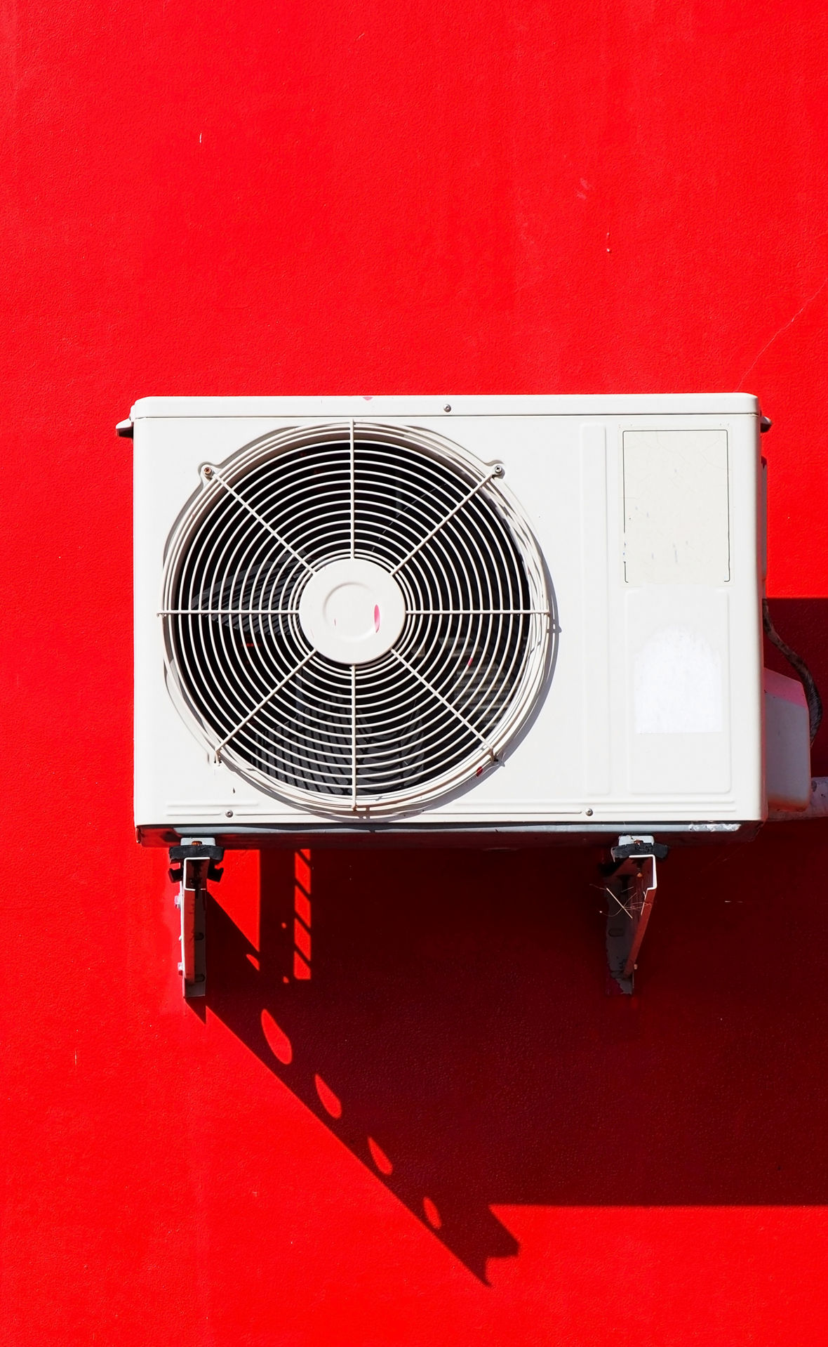 An air conditioner on a red wall