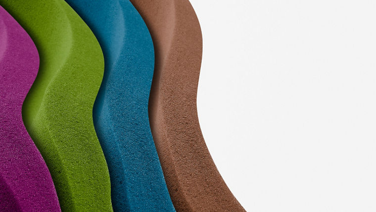 Close-up of layered colored powders in purple, green, blue, and brown, arranged in wavy patterns—symbolizing TEGO® Color’s vibrant pigment range.