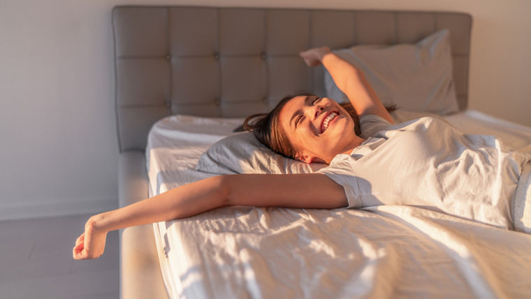 Person lying on a bed with white sheets—representing Evonik’s PU additives for high-quality, sustainable slabstock foam in bedding and comfort products.