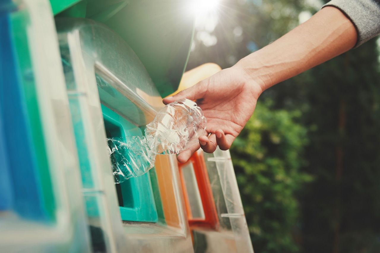 people putting plastic bottle in to recycle bin at park