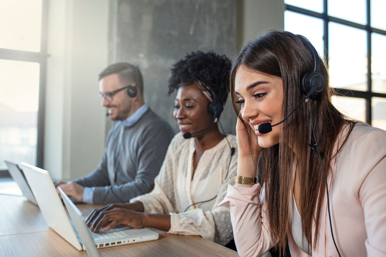 Customer service executive working at office. Colleagues working in a call center. Beautiful business people in headsets are using computers and smiling while working in office. 