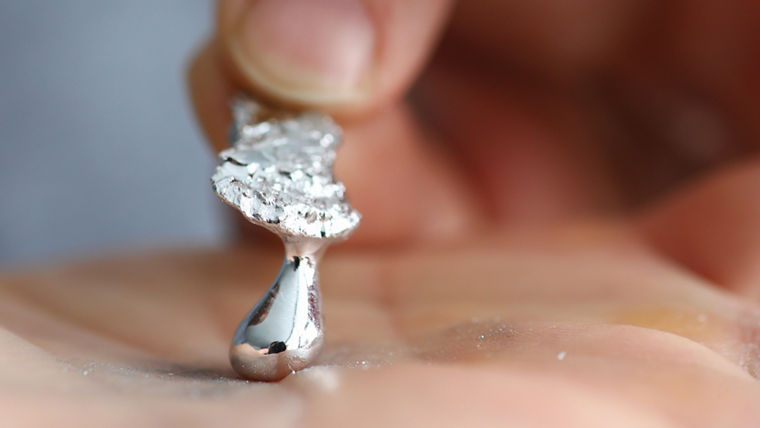 Male hand holding piece of liquid gallium