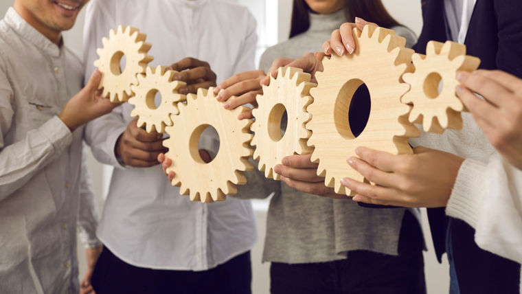 Group of people joining gears as metaphor for collaboration and building effective business system