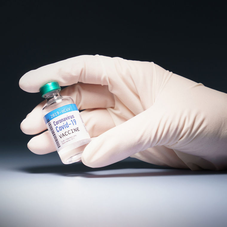 Hand eines Forschers, der eine Ampulle mit Coronavirus, SARS-CoV-2, im Scheinwerferlicht hält.