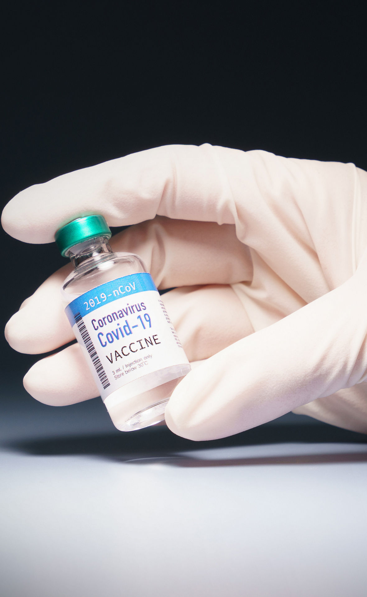 Hand of a researcher holding an ampoule with coronavirus, SARS-CoV-2, in spotlight.