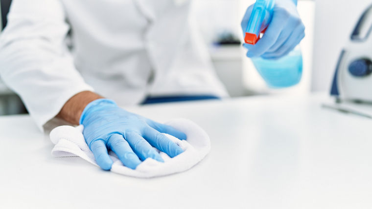 Handsome hispanic man working as scientific cleaning the table at laboratory