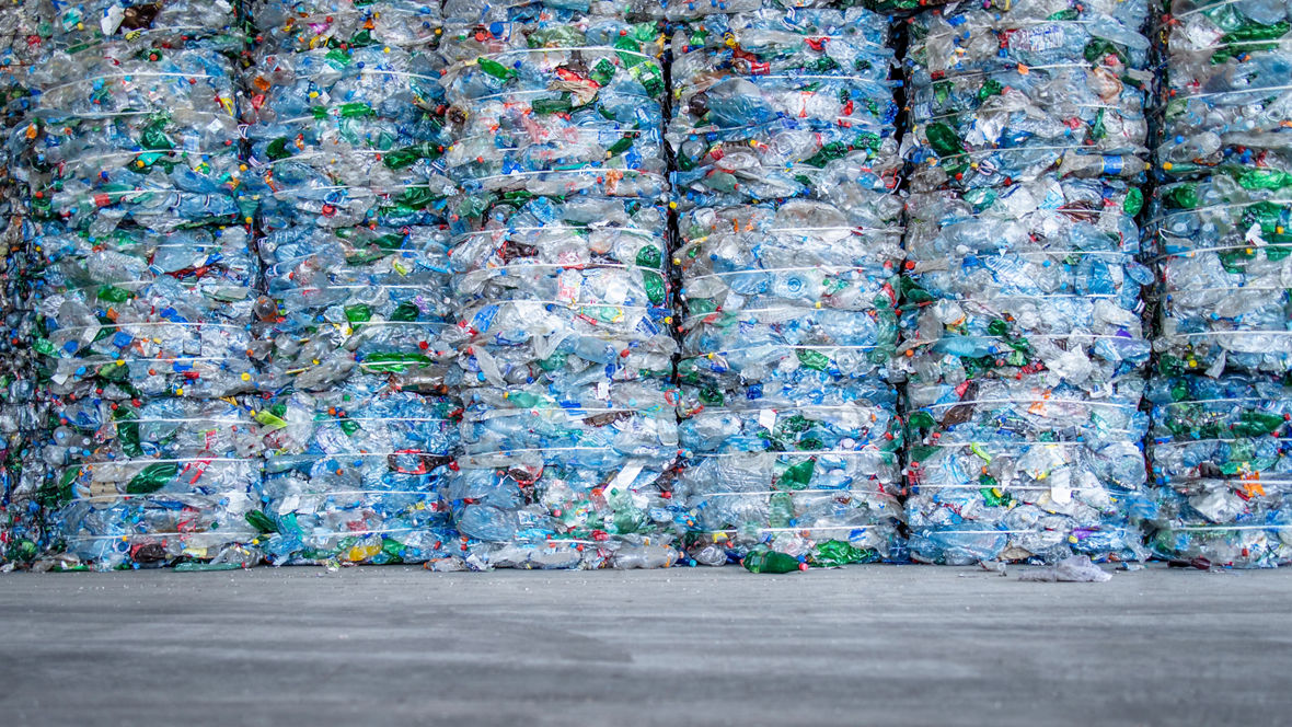 A large pile of plastic PET bottles, compressed and ready for recycling.