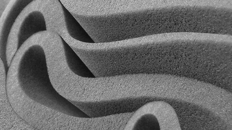 Close-up image of gray polyurethane foam with intricate wave-like patterns, representing the advanced performance of Dabco® catalysts in foam structure.