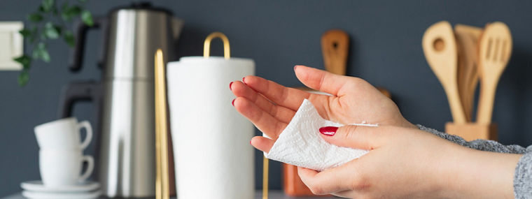 A woman wipes his hands with a paper towel in the kitchen. Napkins for care, domestic