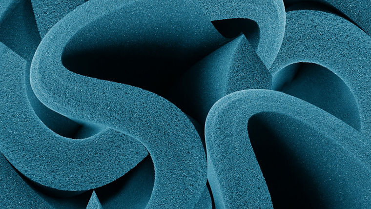 Close-up of blue polyurethane foam with interlocking shapes, illustrating the structural impact of KOSMOS® catalysts.