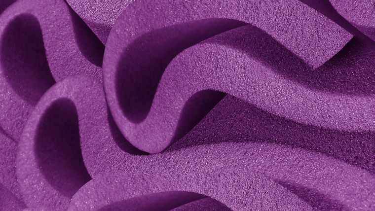 Close-up of purple foam with wavy, undulating patterns, representing the enhanced surface properties enabled by ORTEGOL® additives.