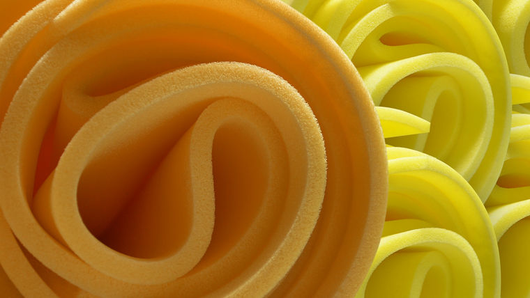 Close-up of rolled yellow foam sheets with a smooth texture, arranged in a visually appealing pattern—highlighting GORAPUR®'s flexible foam solutions.