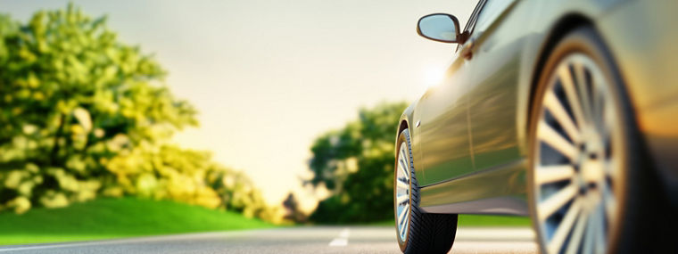 Car on sunny road with green landscape