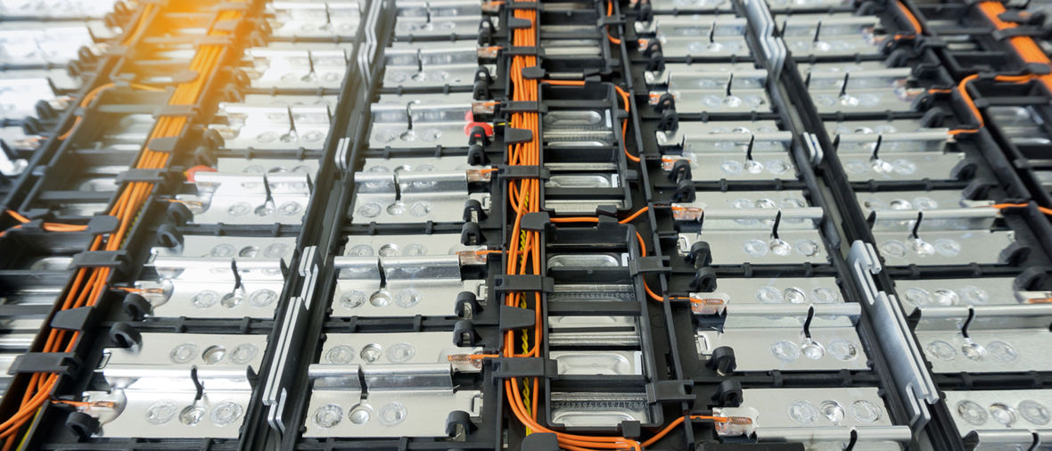 Electric vehicle lithium-ion battery pack with rows of cells connected by orange cables.