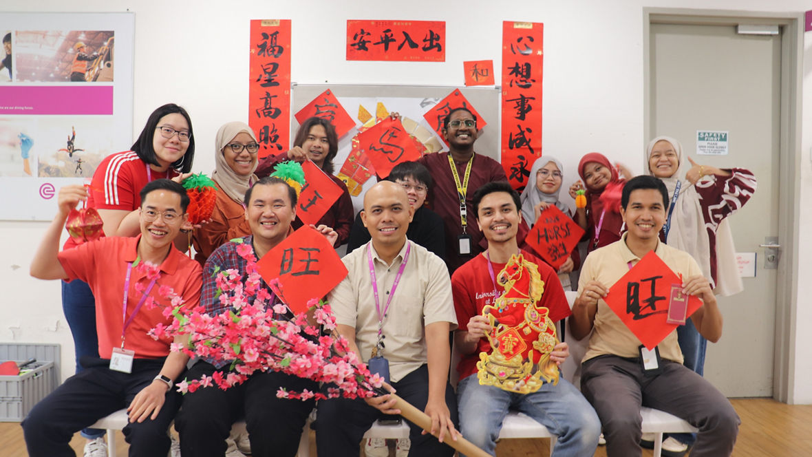 Group of people celebrating Chinese New Year with traditional decorations and red banners.