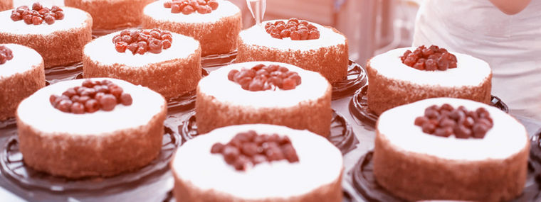 Pastry chef girl makes a cake from fresh biscuit berries and cream. Mass production of cakes and sweets, confectionery factory