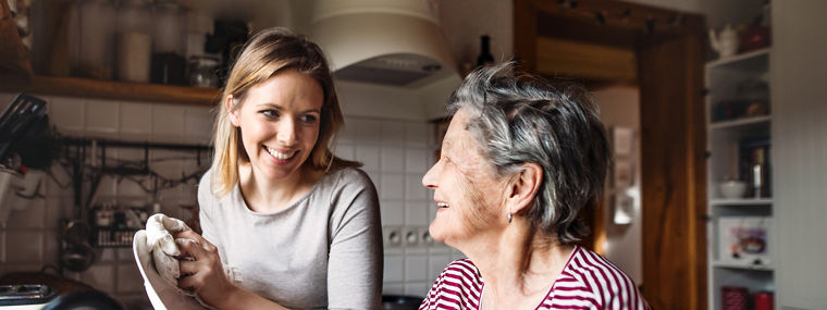 Eine ältere Großmutter mit einem Erwachsenen Enkelin zu Hause das Geschirr abwaschen.