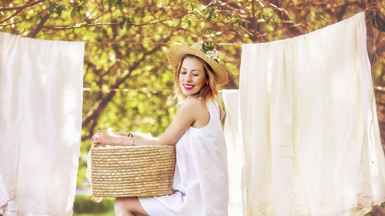 Beautiful young and happy woman hanging clean Laundry in the garden