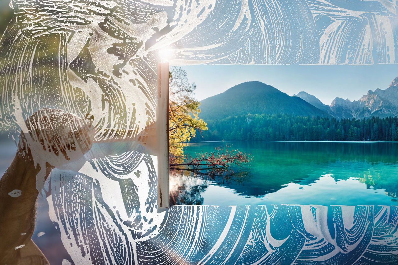 Window cleaner using a squeegee to wash a window with clear blue sky