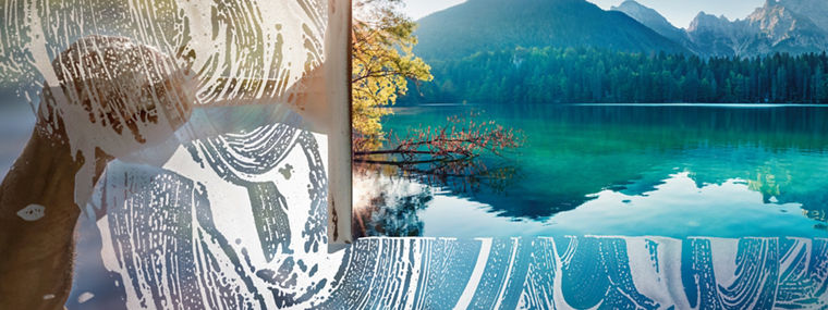 Window cleaner using a squeegee to wash a window with clear blue sky