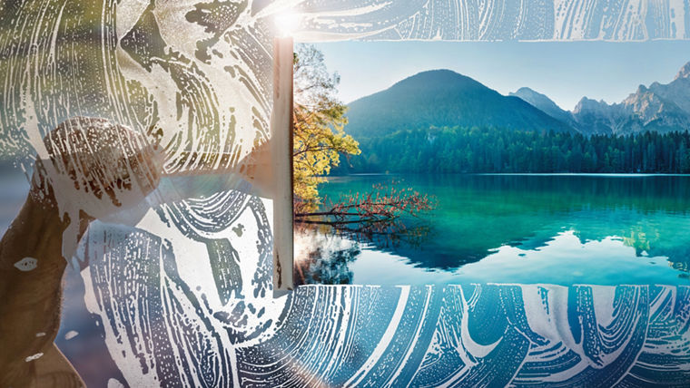 Window cleaner using a squeegee to wash a window with clear blue sky