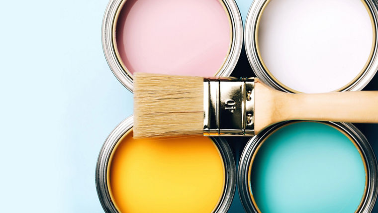Banner of renovation concept. Brush with wooden handle on opened cans on blue pastel background. Yellow, white, pink, turquoise colors. Macro.
