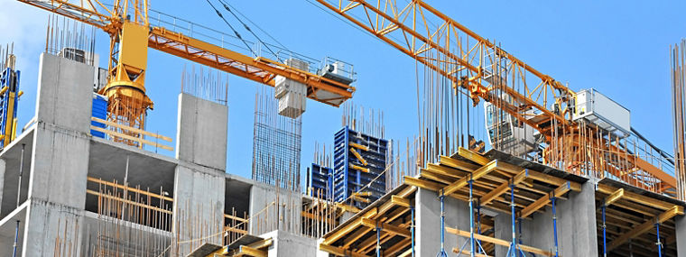 Crane and building construction site against blue sky