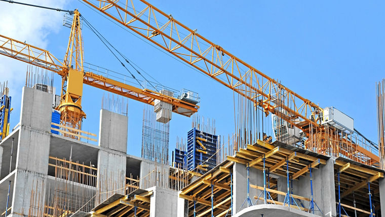 Crane and building construction site against blue sky