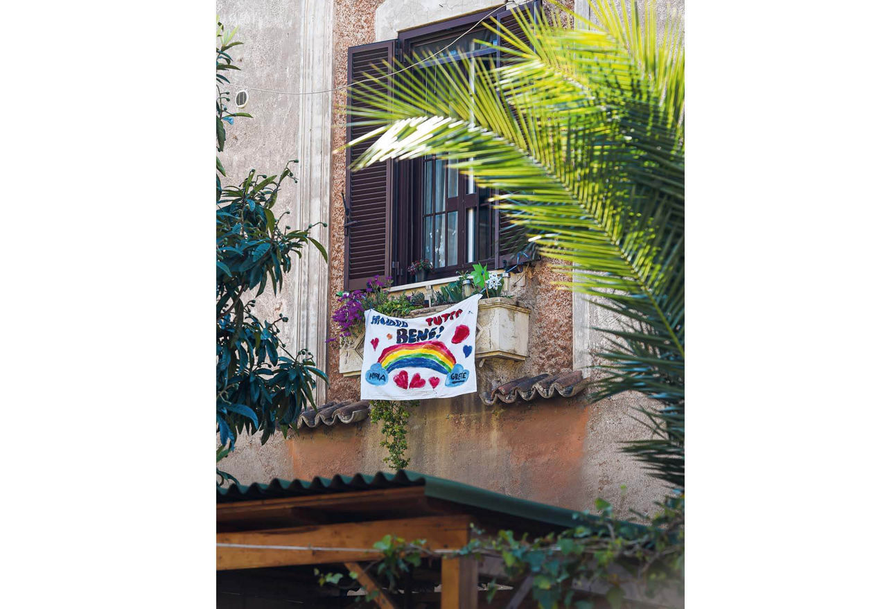 Ein weißes Tuch mit aufgemaltem Regenbogen und dem Spruch „Andra tutto bene“.