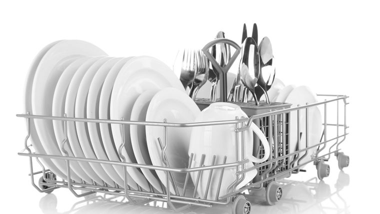 Clean dishes drying on metal dish rack, isolated on white
